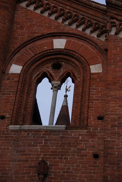Gothic brick mullioned window with terracotta spire behind