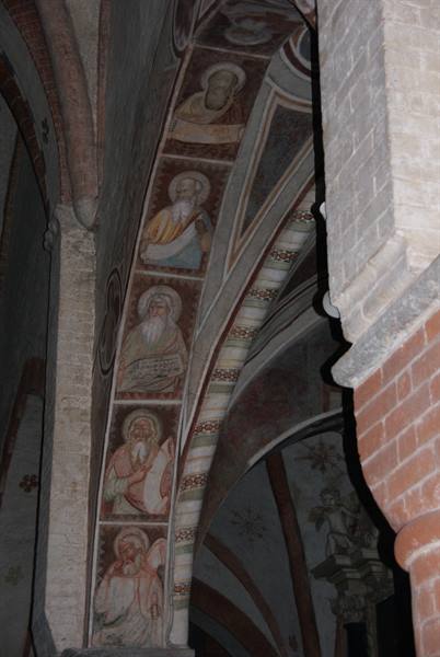 Arch frescoed with saints inside a medieval brick church