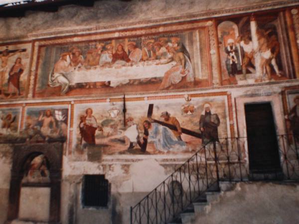 Faded ancient frescoes depicting the Last Supper and Passion above a staircase