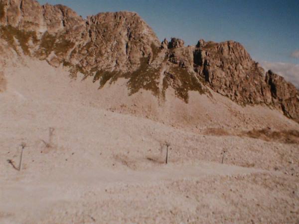 Rocky crags rising above a mountain ski lift slope