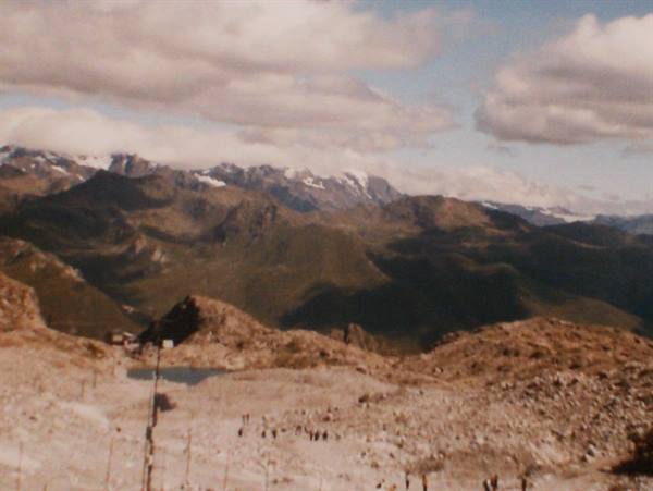 Rocky mountains with distant snow, clouds and hikers below