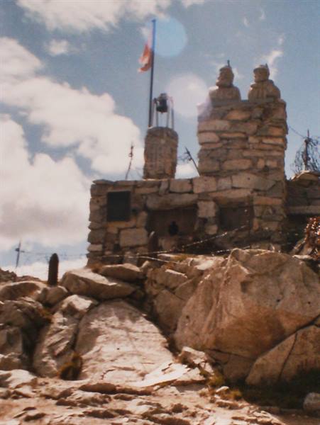stone building with bells and flag on rocky mountain summit