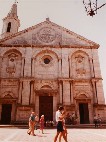 Tourists walk across the square in front of Pienza Cathedral's Renaissance facade