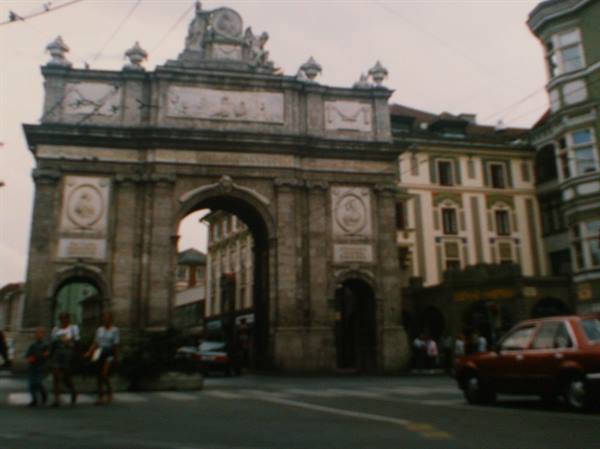 Stone triumphal arch in Innsbruck, pedestrians and cars crossing the street