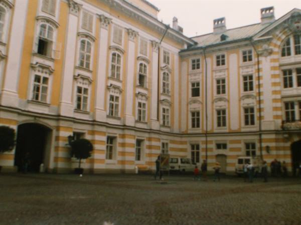 Cobblestone courtyard in front of a yellow and white baroque palace