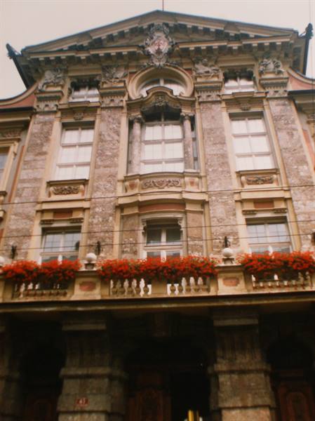 Baroque stone facade with balcony of red geraniums under soft light