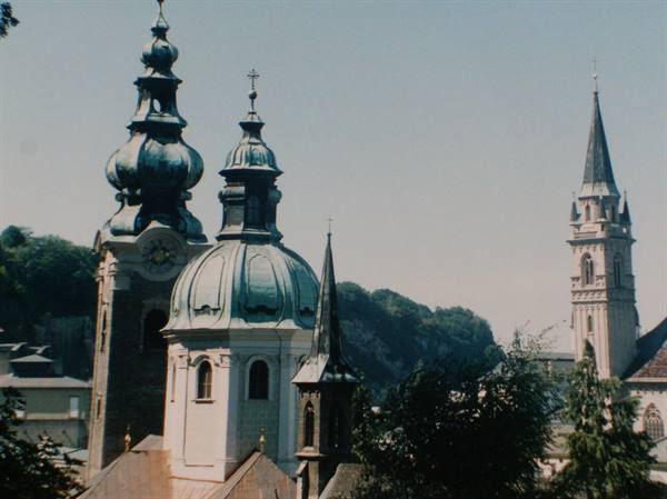 Green domes of Salzburg and the Gothic bell tower under a blue sky