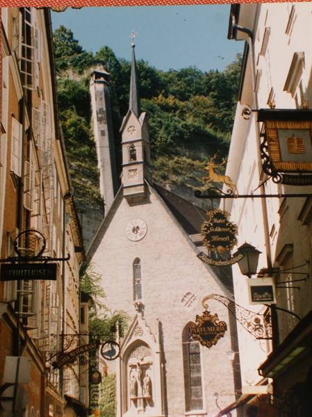 Gothic church spire between wrought-iron signs, Salzburg