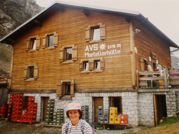 Smiling woman in front of the wooden Martellerhütte hut at 2610 meters