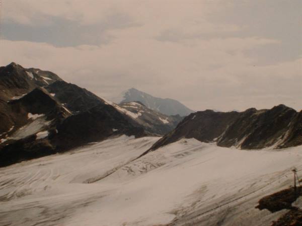 Glacier between snowy rocky peaks under overcast sky, soft light