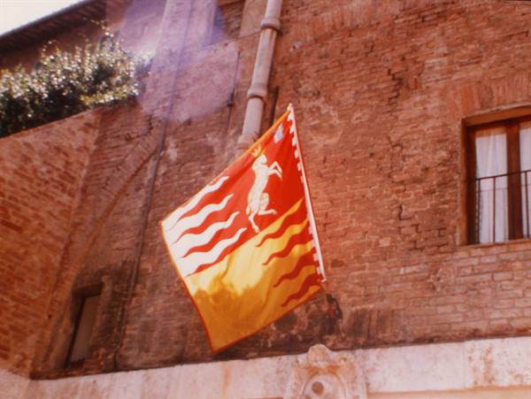 Red and yellow banner with white horse hung on a brick wall