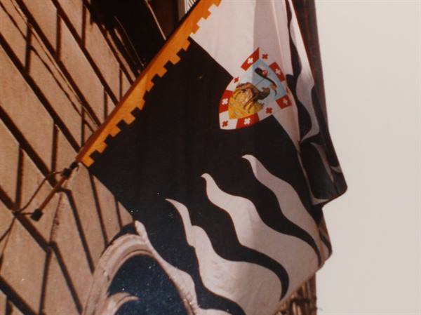 Siena's black-and-white flag with coat of arms on a brick building