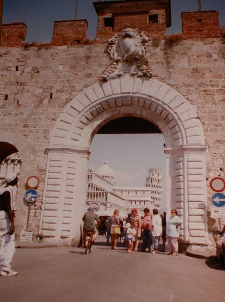 Porta Nuova gate in Pisa, tourists under arch, cathedral and leaning tower behind