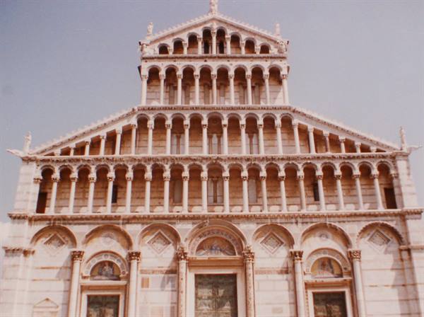 Marble facade of Pisa Cathedral, rows of columns under a blue sky