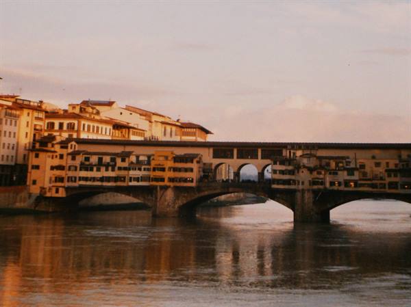 Ponte Vecchio in Florence, stone arches over the Arno in golden light