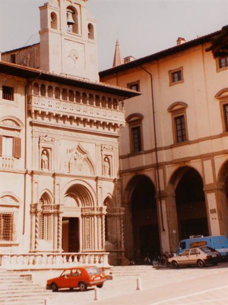 Marble Renaissance church with bell tower, parked cars below, Prato