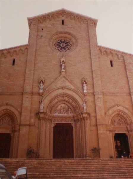 Stone facade of Arezzo Cathedral with rose window and statues