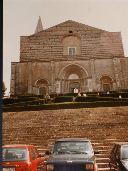Facade of the Basilica of San Francesco in Assisi, steps with parked cars