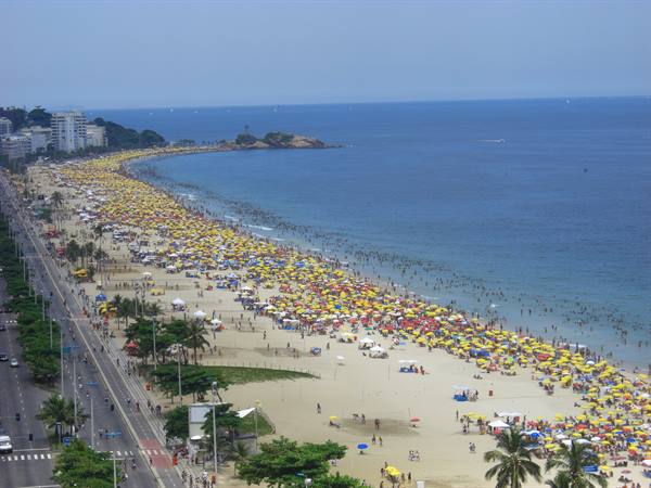 Crowded beach with yellow umbrellas and swimmers along the ocean, Copacabana