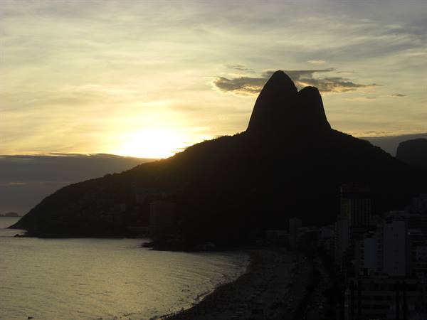 Dois Irmãos mountain silhouetted over the ocean at dusk