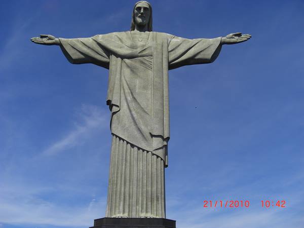 Christ the Redeemer statue in Rio de Janeiro, arms outstretched against blue sky