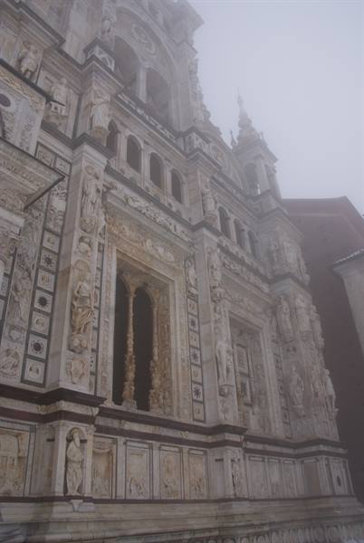 Marble facade of the Certosa di Pavia in the fog, statues and carved reliefs