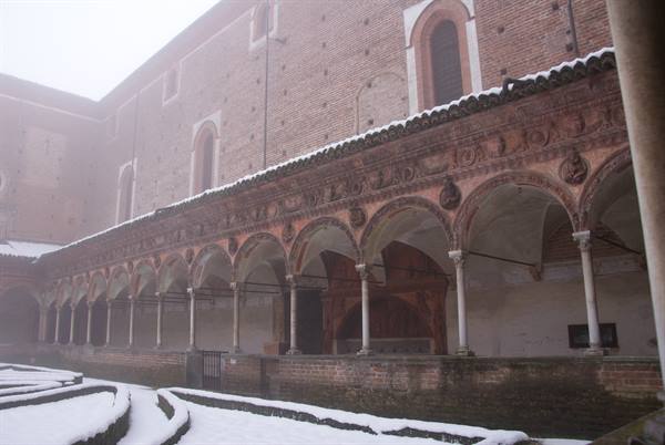 Foggy cloister with terracotta arcades and snow, Certosa di Pavia