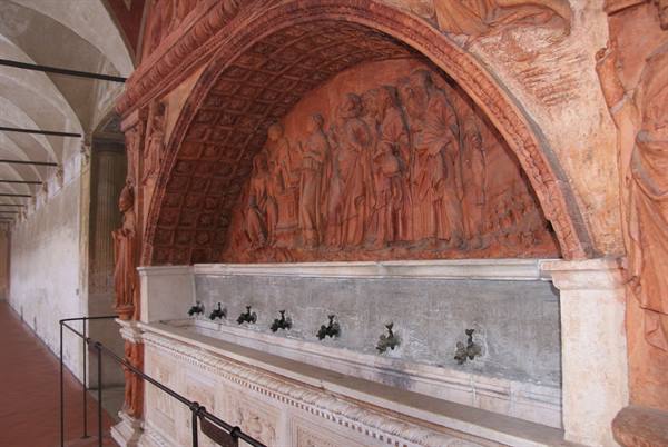 Terracotta and marble fountain with bronze spouts beneath carved reliefs