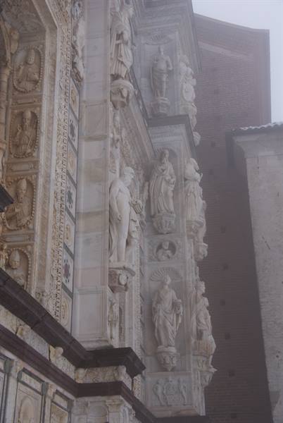 Marble statues on the Certosa di Pavia facade shrouded in fog