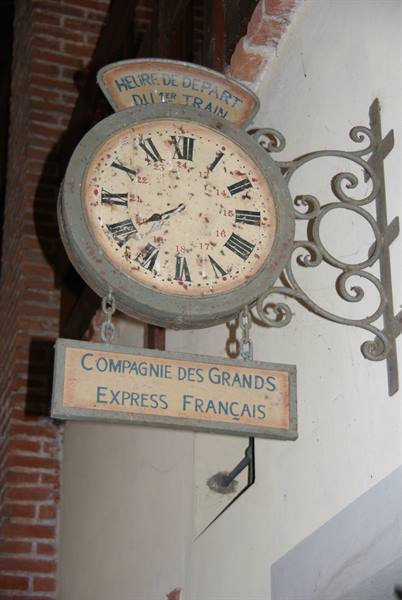 Old clock hanging with Compagnie des Grands Express Français sign on brick wall