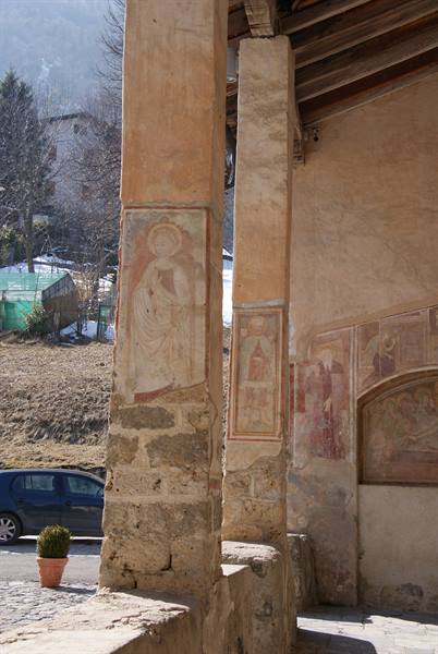 Stone columns with medieval frescoes under a mountain church portico
