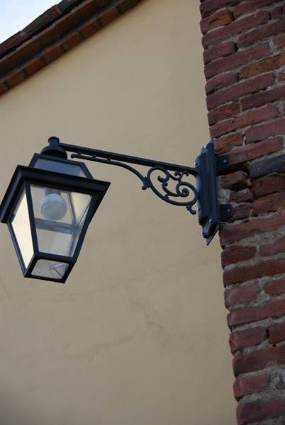 Black wrought iron lantern hanging on a red brick wall