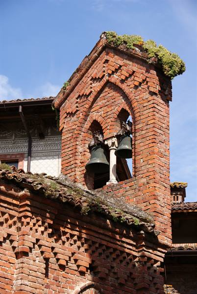 Red brick bell tower with two bronze bells under gothic arches