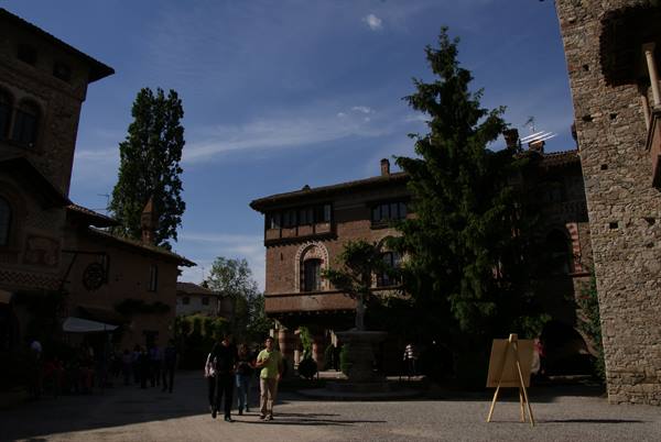 Grazzano Visogli: tourists stroll among brick houses and an easel