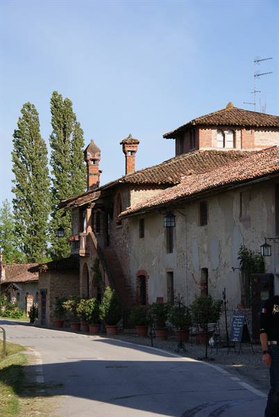 Old brick farmhouse with tiled roofs and chimneys along the road