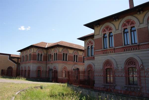 Red-brick buildings with arched windows and iron fences under blue sky
