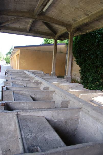 Public washhouse with stone basins under a concrete canopy