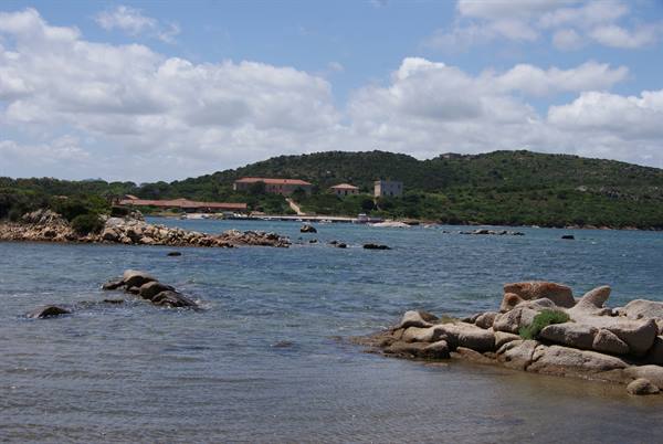 Granite rocks in turquoise water, green hill with houses behind