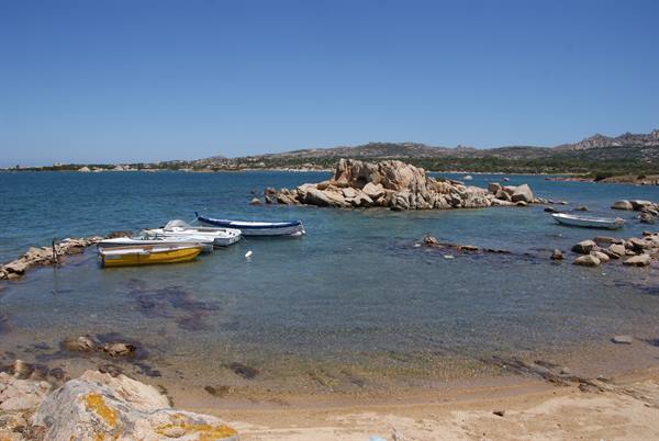 Colorful boats moored among granite rocks in turquoise water, Mediterranean coast