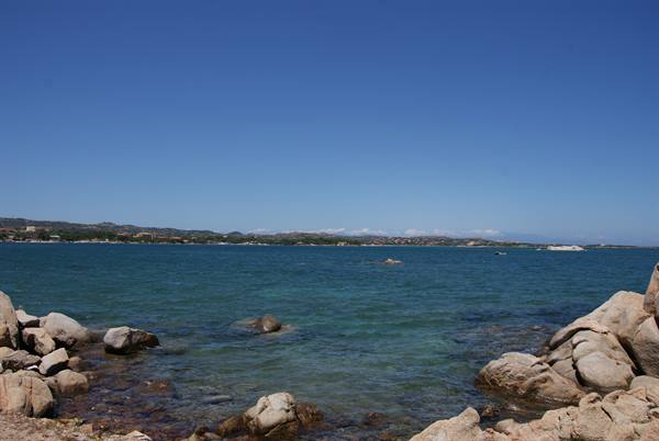 Granite rocks on turquoise water, coastline with boats under blue sky