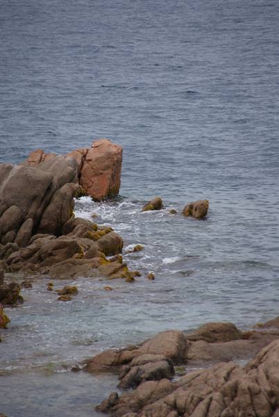 Pink granite rocks by the sea, waves crashing, soft diffused light
