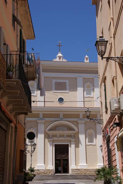 White church with neoclassical facade seen between old buildings and wrought-iron lamps