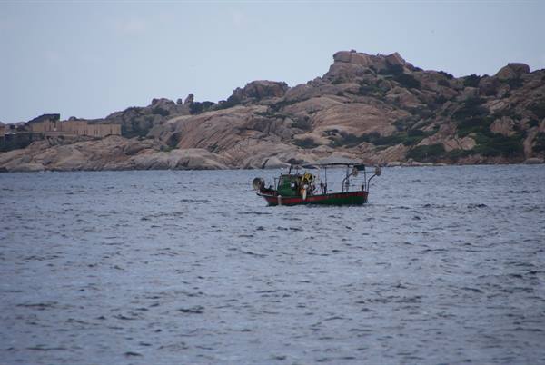 Fishing boat on the sea in front of granite cliffs