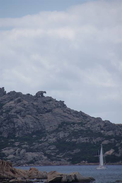 White sail by granite rock formation above the sea