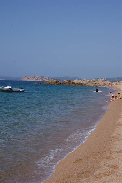 Boat anchored off the sandy beach, swimmers in clear turquoise water