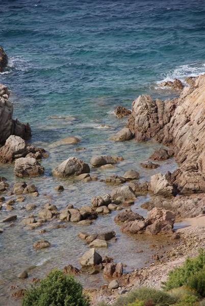 Granite rocks between turquoise water and foam, Mediterranean shrubs below