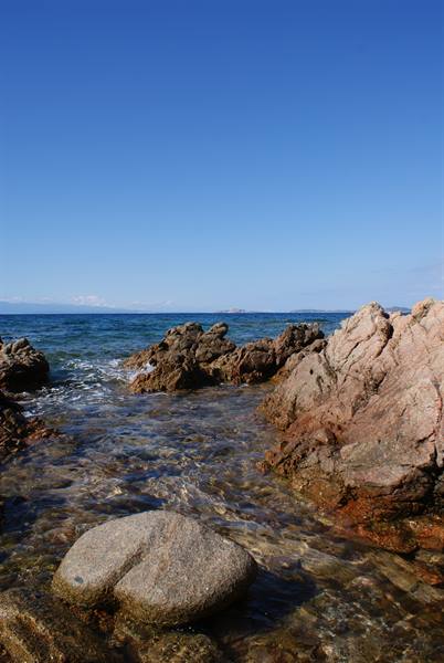Pink granite rocks and clear water under a blue sky