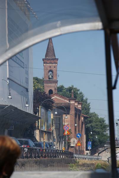 Brick bell tower seen from boat canopy, traffic along the canal
