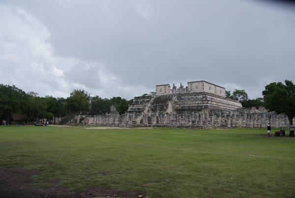 Temple of the Warriors at Chichén Itzá, Mayan stone under cloudy sky, green lawn ahead