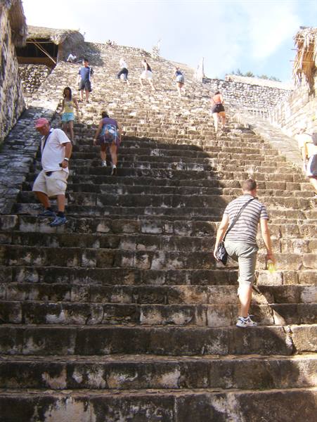 Tourists climb the steep stone steps of a Mayan pyramid at Cobá
